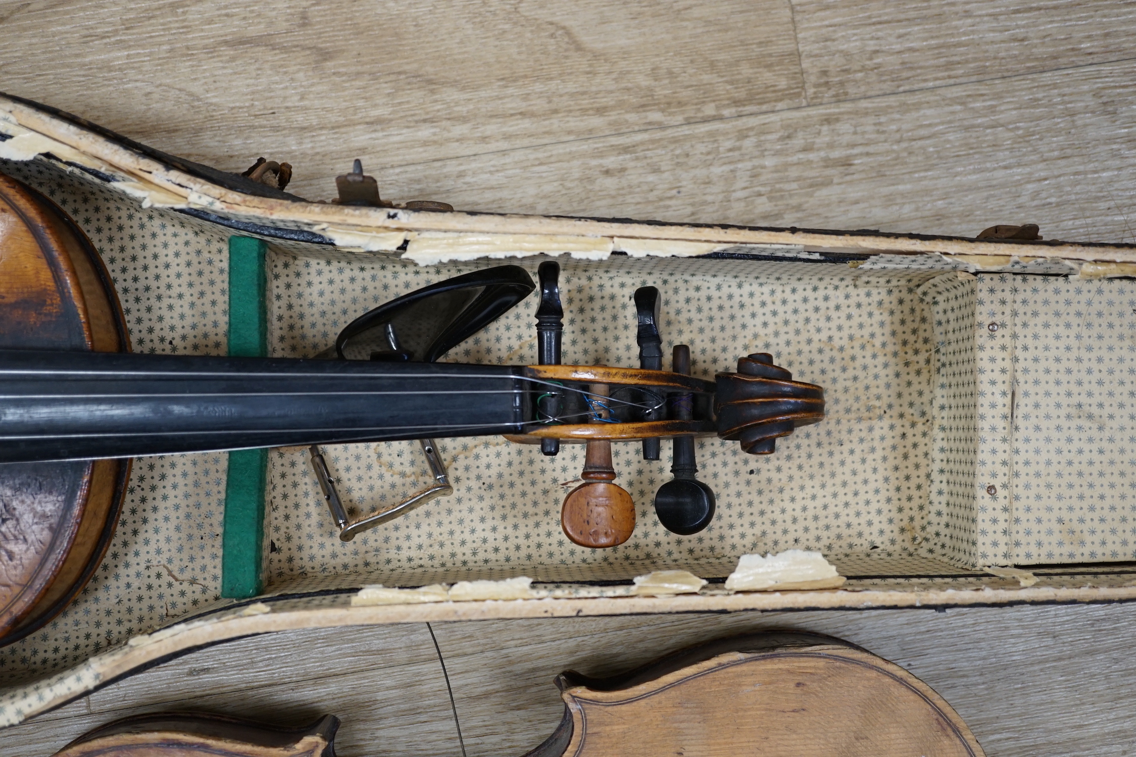 Two early 20th century violins, one in the remains of a case, both for restoration, length of bodies, 35.5cm and 36cm